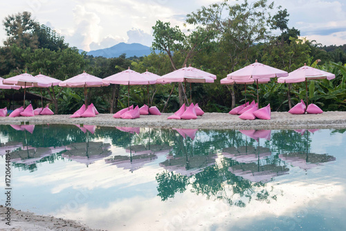 Pink umbrellas on the artificial sea behind are beautiful green mountains