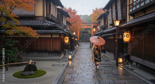 Traditional Japanese street in autumn with a geisha walking under an umbrella, illuminated by lanterns during dusk in Kyoto.