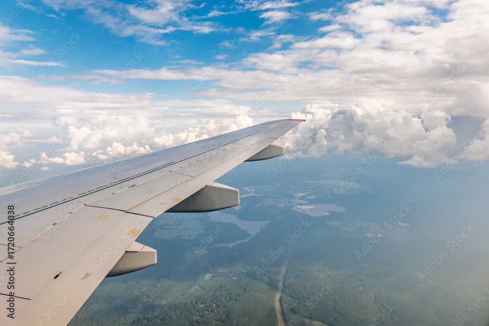 Fototapeta premium View from the airplane window at a beautiful cloudy sky and the airplane wing