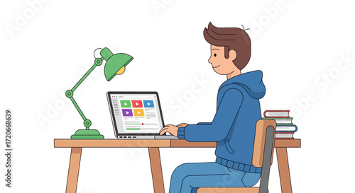 A young man is sitting at a desk, working on a laptop computer with a green desk lamp.