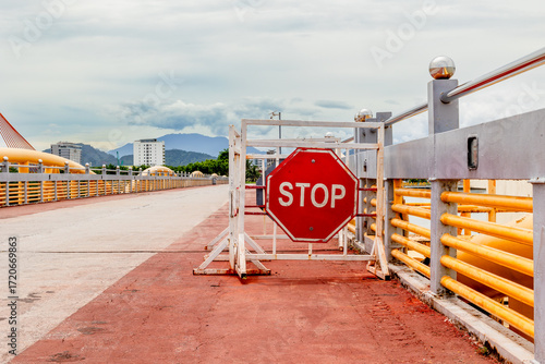 Stop sign on bridge walkway with city and mountain view in background