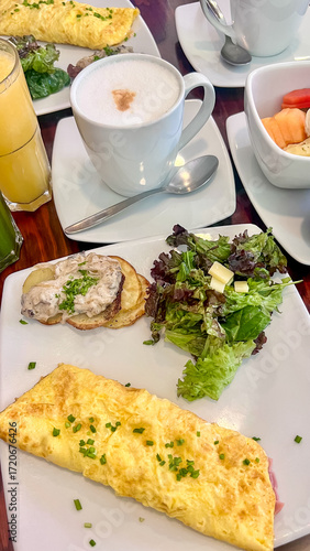 Healthy delicious breakfast in a restaurant with omelet, fresh salad, coffee and juice. Balanced morning meal. Vertical photo.