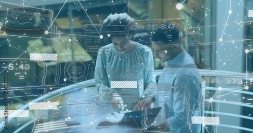 Colleagues meeting in atrium using devices creating data overlay and refining engineering plans