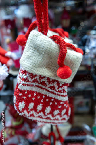 Close-up of a red and white festive knitted Christmas stocking. This decorative stocking has a soft and warm texture and is perfect for hanging on the tree. Christmas decorations. Vertical photo.