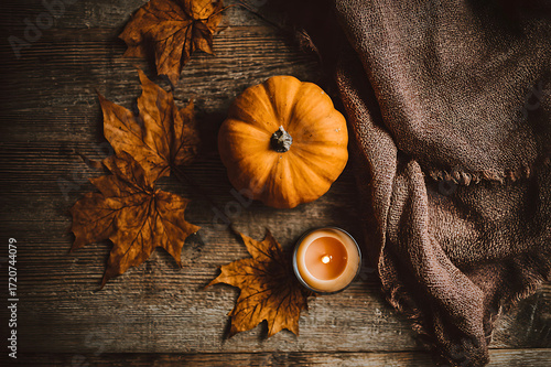 Cozy autumn still life with mini pumpkin candle and fall leaves on rustic wood