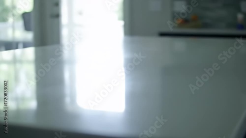 White Countertop Reflecting Bright Window in Blurred Kitchen Environment