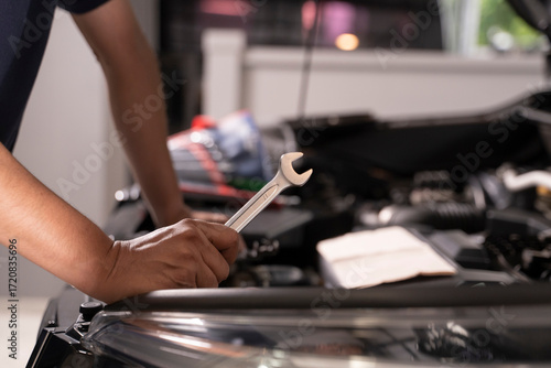 A man with a wrench is ready to do some basic car maintenance.