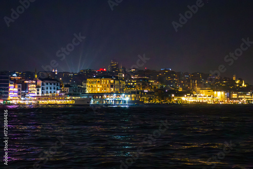 Istanbul, Turkey - November 8, 2023: view of Istanbul waterfront with brightly lit buildings, luxury hotels, and historical architecture reflecting in the Bosphorus waters. The vibrant atmosphere of