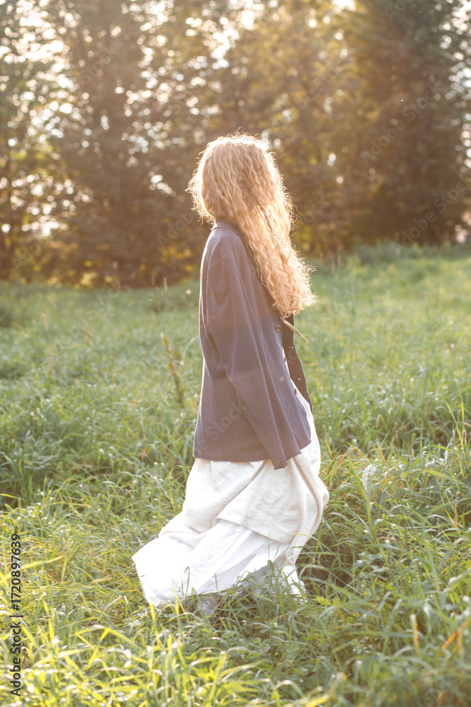 Fototapeta premium Fashion portrait of young hippie woman at sunset posing on nature background