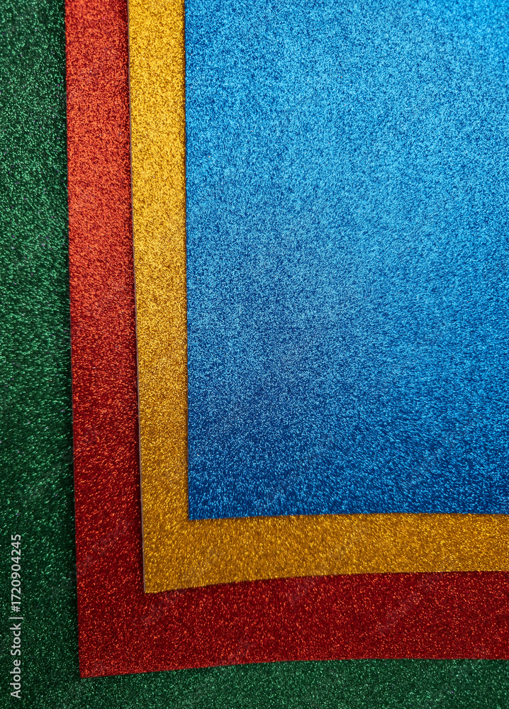 Fototapeta premium Stack of glittery green, red, yellow, and blue textured craft paper sheets