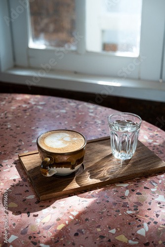 Hot coffee latte with latte art milk foam in cup mug on marble floor desk As breakfast In a coffee shop at the cafe, during business work concept