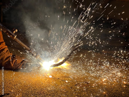 Industrial welding with sparks flying in the dark – high heat, craftsmanship, and metalworking process captured in action.