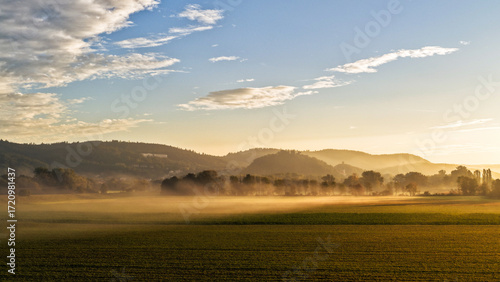 Golden Morning Mist Over Wide Farmland and Distant Hills