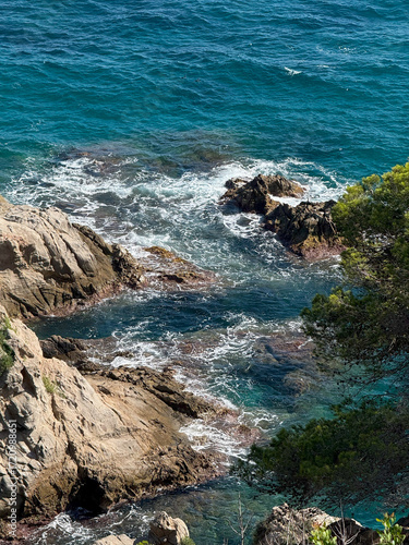 Dramatic rocky sea cliffs with ocean waves crashing against rugged coastal landscape under clear sky natural marine scenery