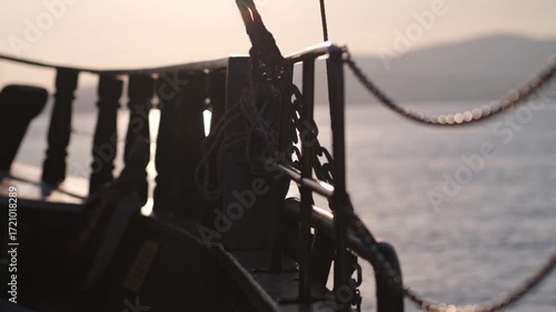 Slow motion close up view from side of vessel. retro style sailing schooner wooden boat boom, lots of ropes, large waves in sunny weather. bow cutting through the water waves at sunset. Travel by sea