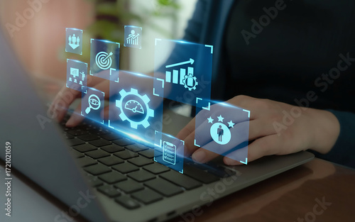 Closeup of hands typing on a laptop keyboard with illuminated digital icons floating above, representing business intelligence and datadriven decision making