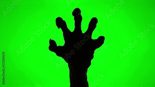 Silhouette of a clawed hand reaching up against a vibrant green background