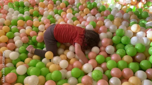 Little Girl Toddler Playing in Colorful Ball Pool in Children Playroom playground