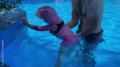 Family Dad and Daughter Swimming in Pool on Sunny Day in Summer with Inflatable Ring