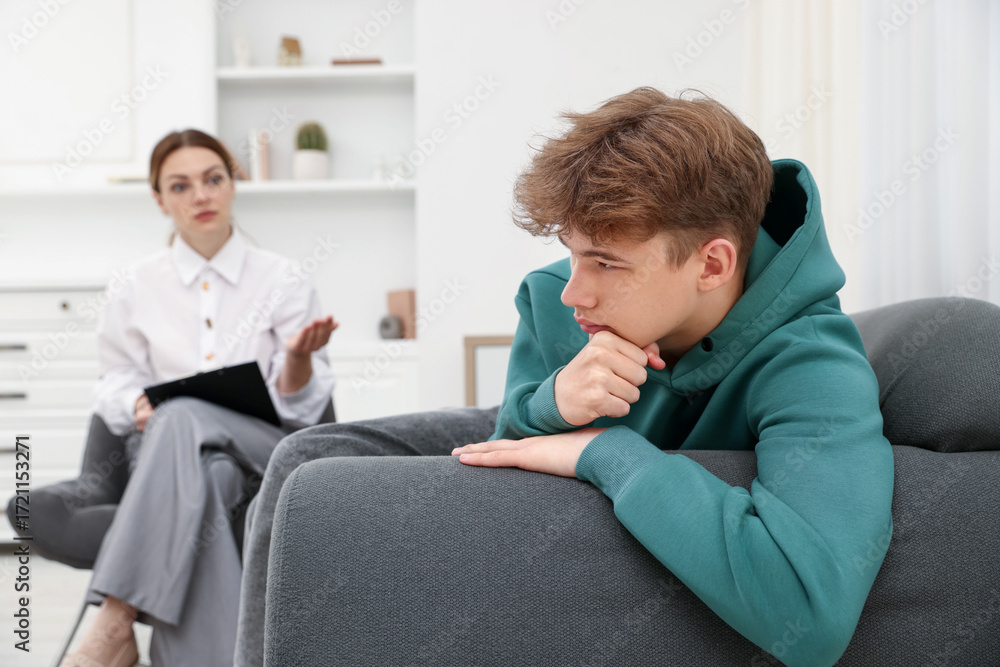 Obraz premium Professional psychologist working with teenage boy in office, selective focus