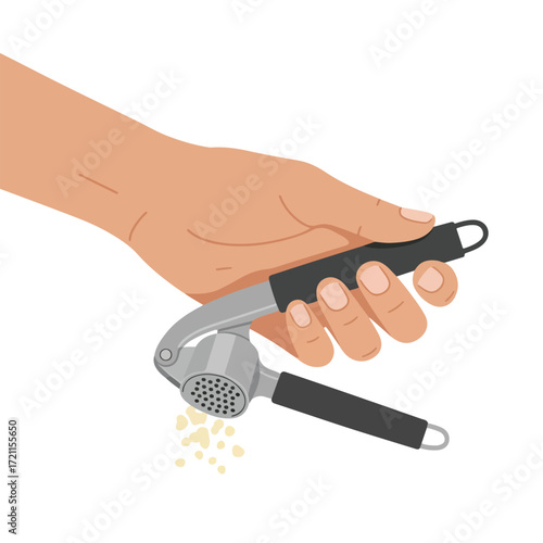 Hand holding & pressing garlic with a steel press, small pieces falling out