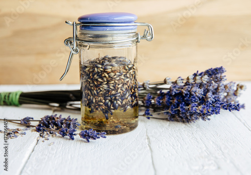 Homemade cold-infused lavender oil. Olive oil covering dried lavender blossoms in a glass jar with bouquet of lavender.