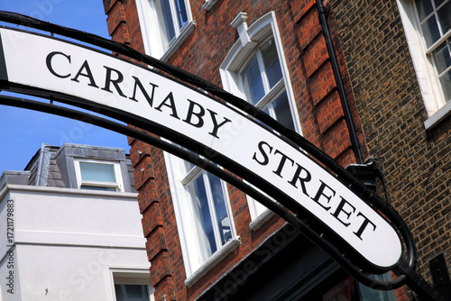 Carnaby Street sign in London England UK were the 1960's hippy flower power fashion started which is a popular tourist travel destination attraction landmark, retail business stock photo image