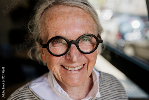Confident smiling woman with glasses in cafe showing self assurance