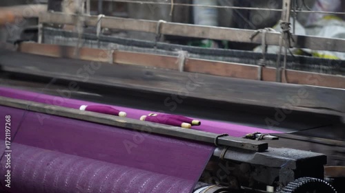 Automated textile weaving loom machine processing purple fabric in Indian factory