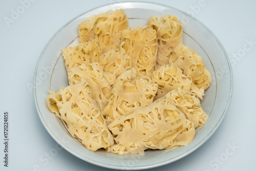 Several roti jala with soft texture and delicate patterns are arranged on a white plate. This traditional Malay dish offers a beautiful presentation that delights the senses and is sure to please the 