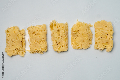 Five golden hued roti jala are neatly arranged. Their fine and tender net like pattern creates a traditional Malay delicacy that is both appetizing and visually appealing.