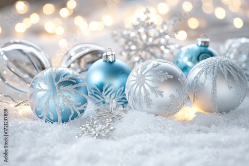 Elegant blue and silver christmas ornaments on sparkling snow with warm bokeh lights in background