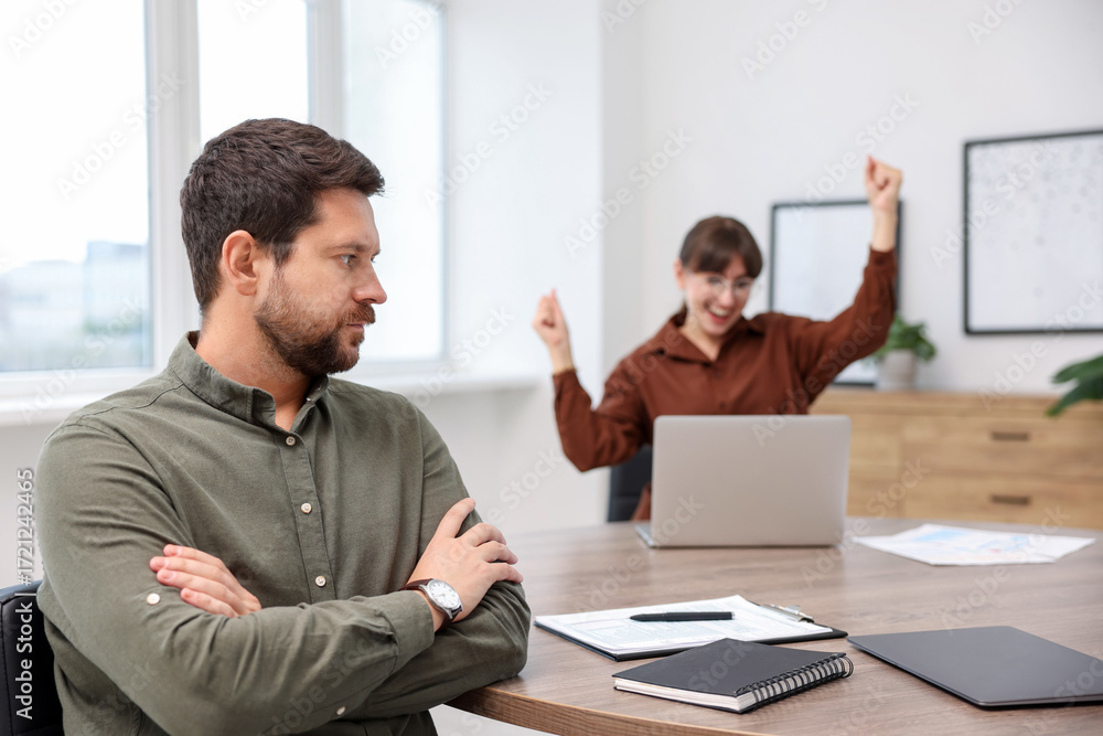 Fotografie Man feeling jealous of his colleague's success in office, selective focus