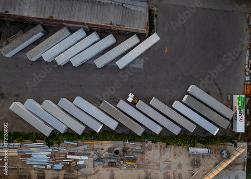 Aerial view of diagonally arranged freight trailers on pavement in an industrial area, creating a geometric top-down view of light and dark. Appleton, Wisconsin, United States.