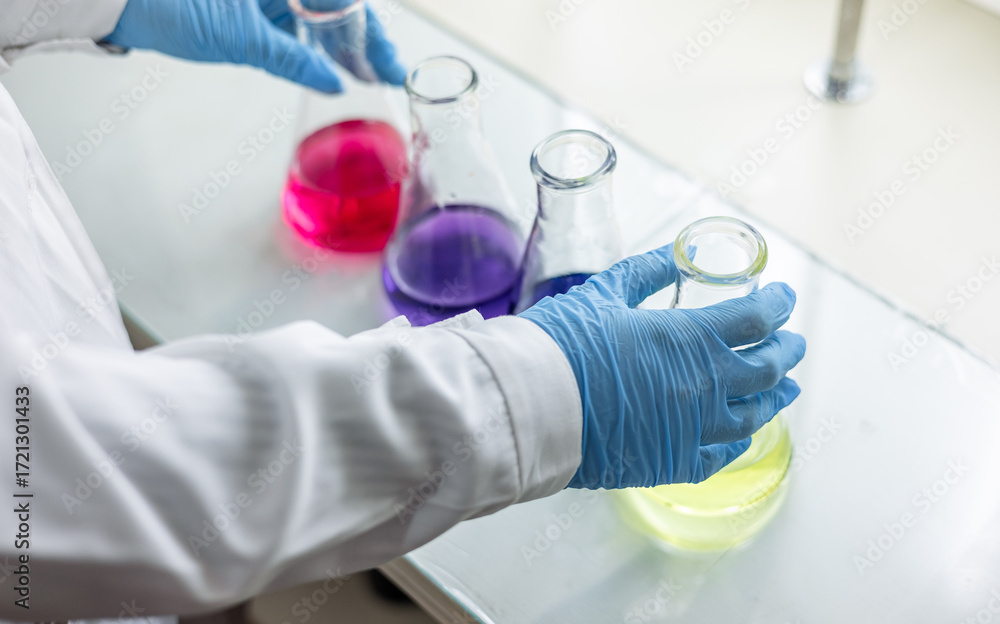 Fototapeta premium The scientist wear blue nitrile gloves holding Erlenmeyer Conical flask, with purple violet solvent forming reaction boric acid and ammonia solution analysis in wastewater sample.