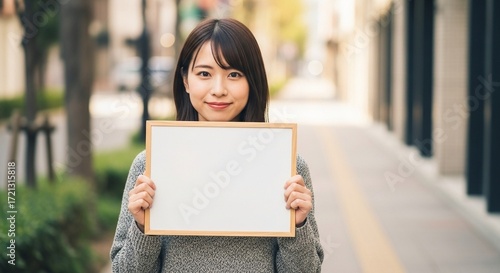 メッセージボードを街中で掲げる日本人女性