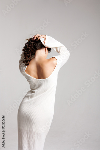 Canvas-taulu Elegant woman in a white dress poses with her back turned in a minimalistic sett