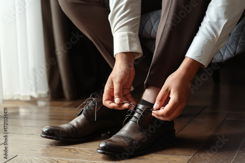 man tying classic black shoes
