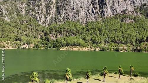 A beautiful lake with green and blue water in a picturesque mountain forest location, on a sunny summer day.