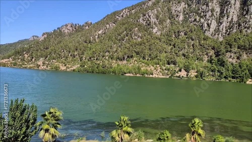 A beautiful lake with green and blue water in a picturesque mountain forest location, on a sunny summer day.