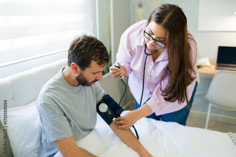 Obraz premium Doctor measuring blood pressure of recovering patient at home