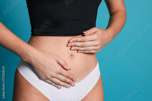 Wallpaper Mural Young woman with flat belly on light blue background, closeup Torontodigital.ca