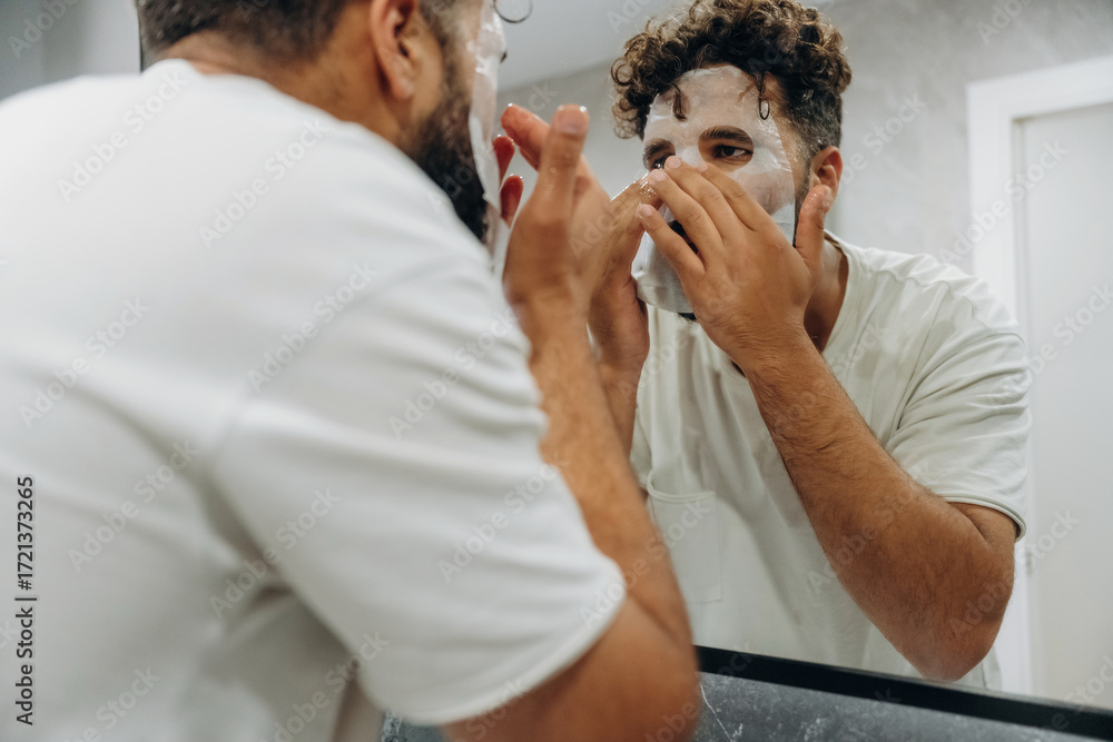 Fototapeta premium Face mask, beauty conception. Guy is in the bathroom, taking care of his appearance