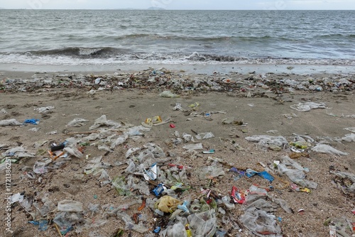 A wide shot of a beach with a visible line of plastic waste and trash stretching across the shoreline.