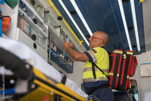 Paramedic preparing medical equipment inside ambulance during emergency