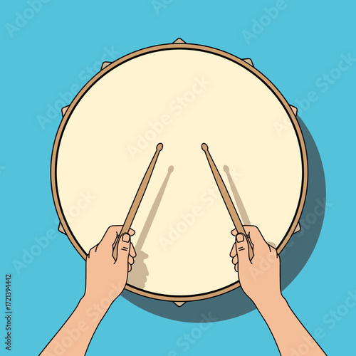 Hands playing a drum with drumsticks against a blue background in a top down view.