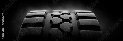Winter tire with deep tread geometry and micro-siping detail, minimalist black-on-black composition
