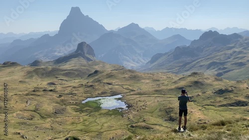Hiker records a panoramic view of the Pyrenees mountain range with his smartphone from the top of a rock