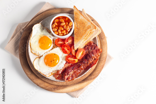 Delicious traditional English breakfast with fried eggs, beans, bacon, tomatoes and toasts