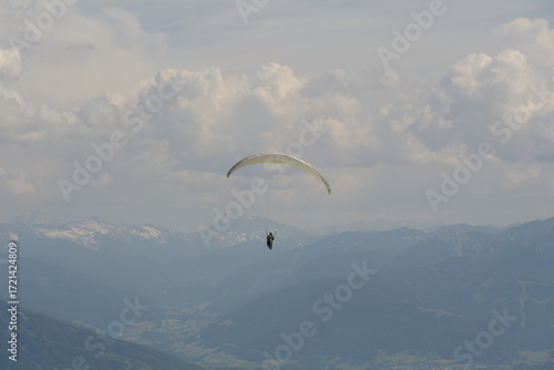A paraglider flies in the mountains